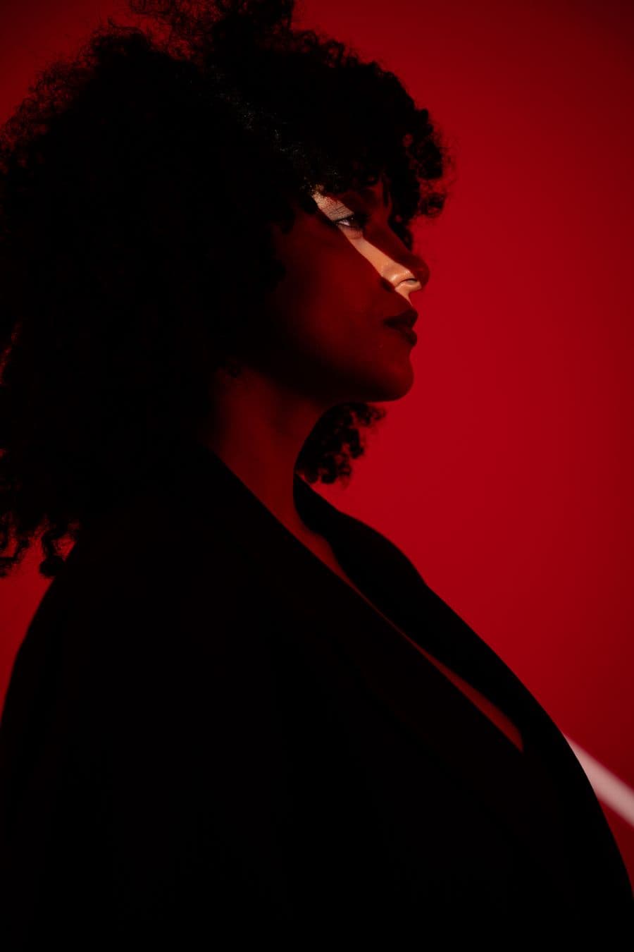 Profile portrait against a deep red backdrop.